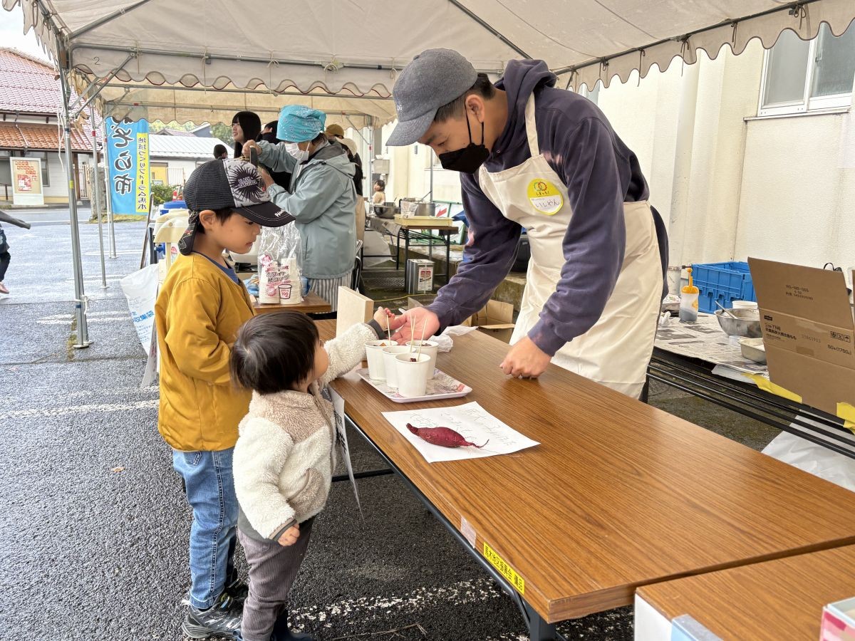 子どもに大学芋を手渡しする編集部いしやん